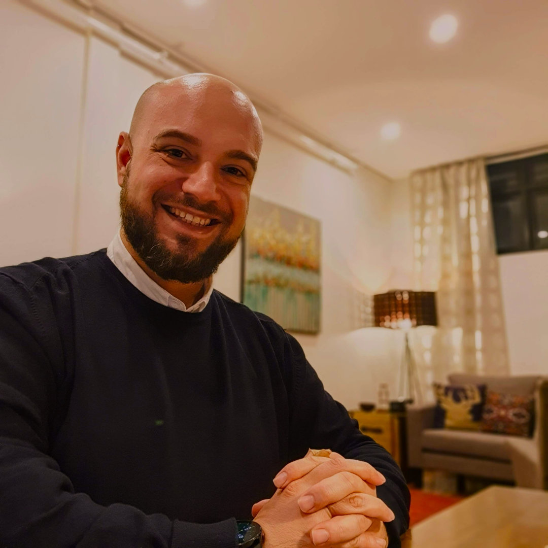 John sitting at a desk, smiling.